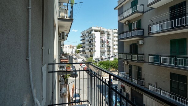 Ein Wohngebäude mit Balkonen, Blick auf die Straße und angrenzende Hochhäuser.