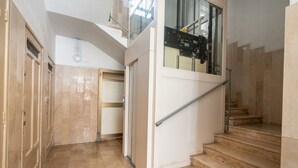Ein Korridor mit einer Treppe, die zu einer zweiten Etage führt, einer Tür mit Griff und einem Fenster mit Metallrahmen.