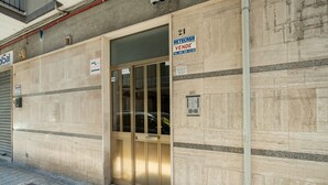 Ein Gebäude mit geschlossenem Garagentor, einem Verkaufshinweis und einer Kontaktnummer.