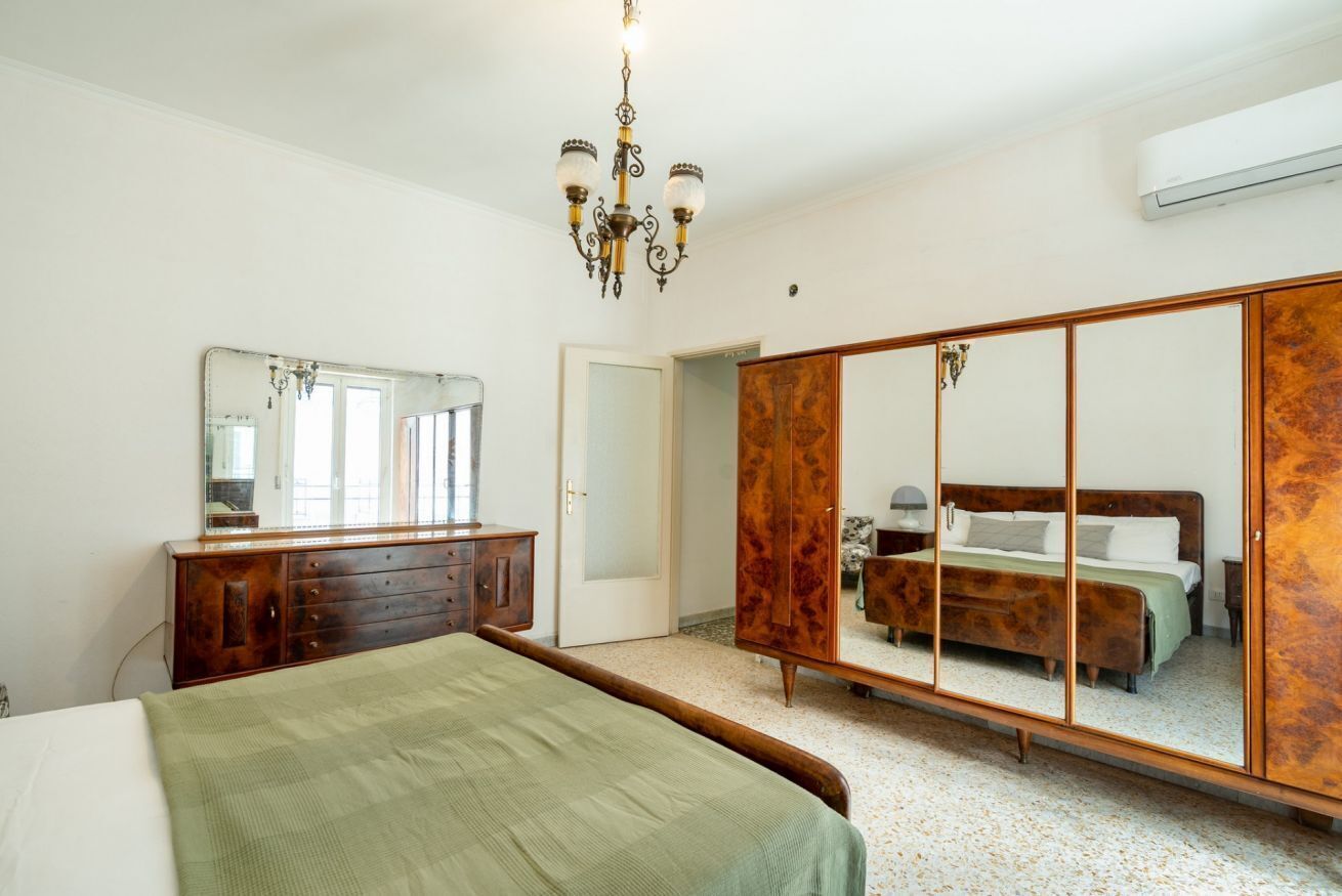 Un dormitorio con cama, cómoda, espejo, armario y candelabro.