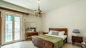 Ein Schlafzimmer mit einem hölzernen Bett, einem Nachttisch, einer Kommode, einem Spiegel und einer Pendelleuchte.