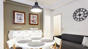 Een eethoek met een ronde tafel, stoelen, een witte kast en wanddecoratie.
