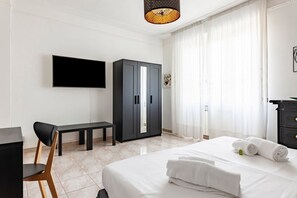 A hotel room with a bed, a desk, a chair, a wardrobe, and a TV on the wall. - GuestHost - San Marco Apartment Mestre (Venice)