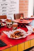Una mesa de restaurante con comida, un recipiente con forma de calavera y un menú.