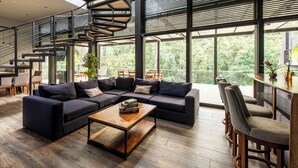 Ein modernes Wohnzimmer mit einem Ecksofa, einem Holztisch und einer Treppe mit Metallgeländer.