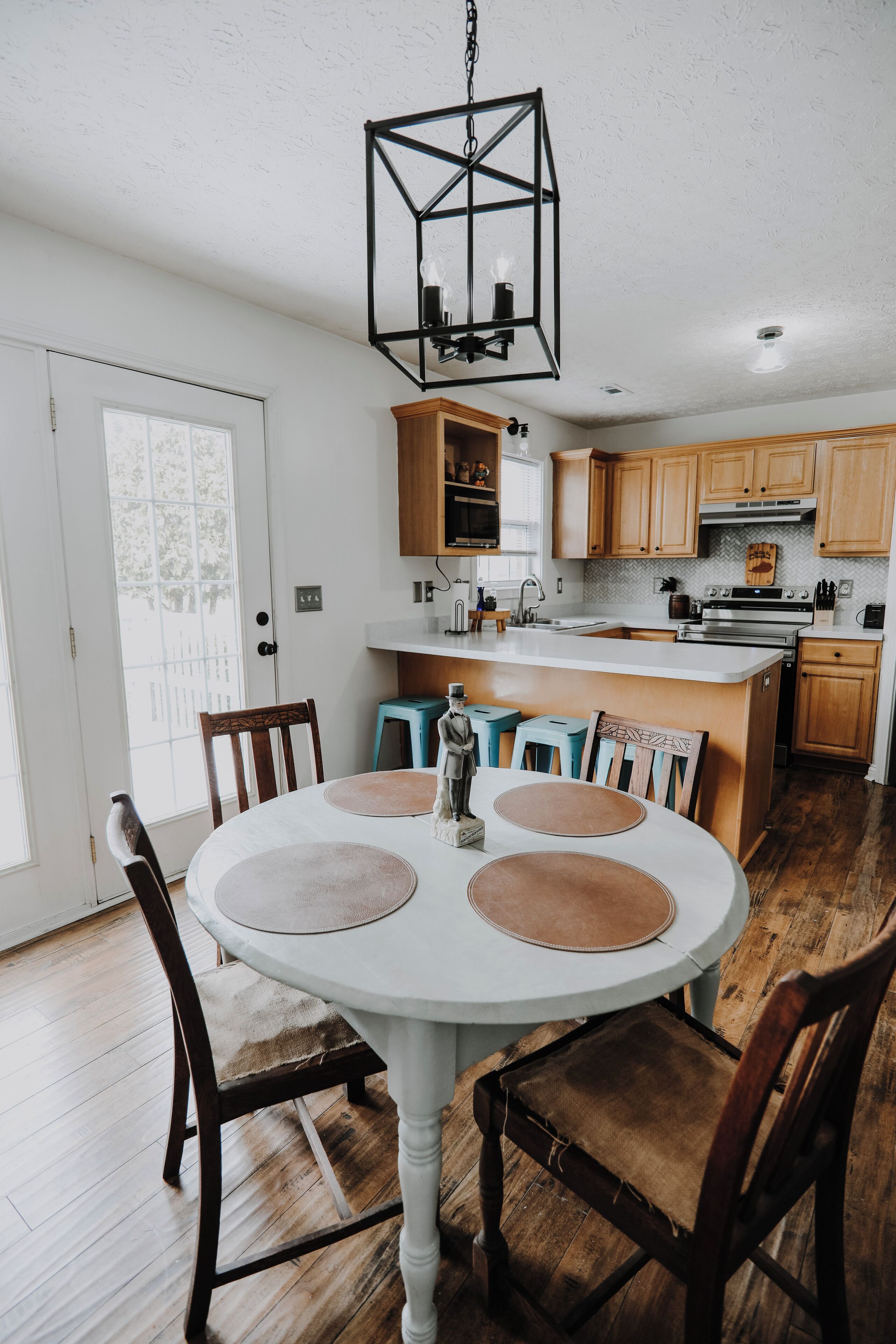 A dining area with a round table, chairs, and a hanging light fixture.