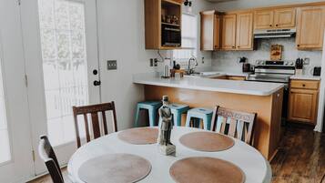 A dining area with a round table, chairs, and a hanging light fixture.