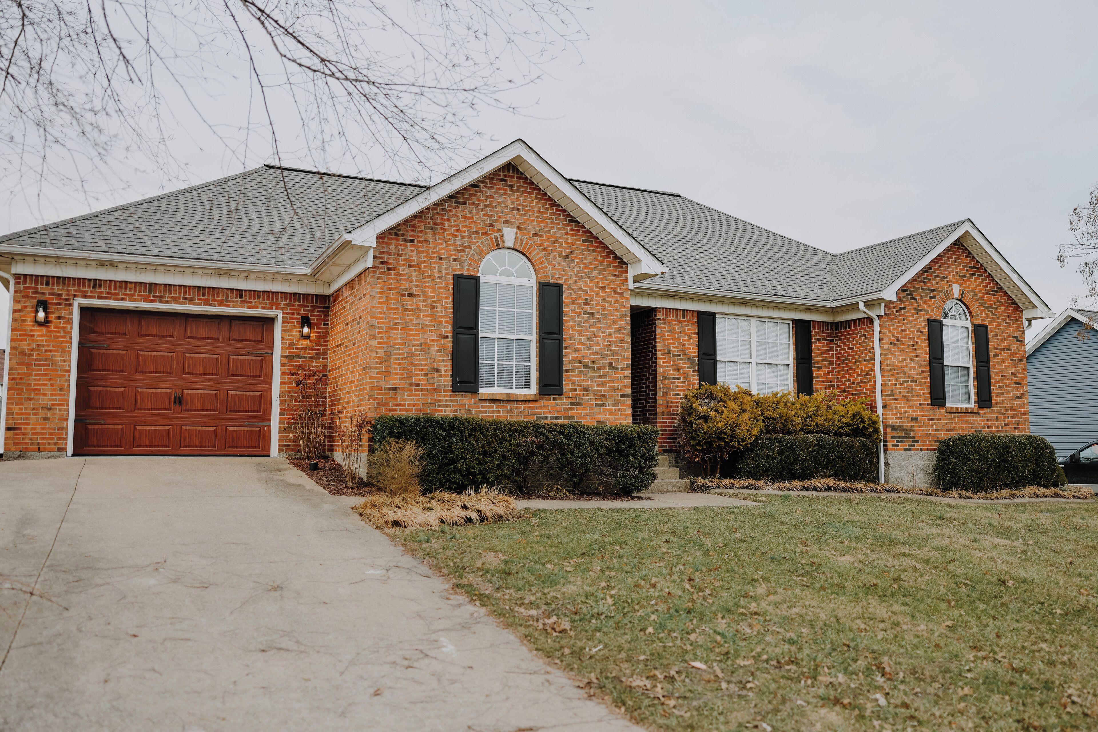 A two-story brick house with a garage, a front lawn, and a driveway.