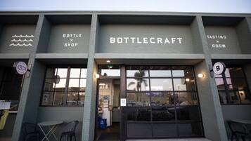A building with a storefront labeled 'BOTTLECRAFT' and a sign indicating a 'TASTING ROOM' on the right.