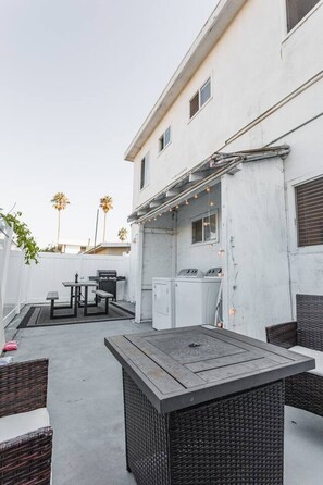 Une terrasse avec mobilier d’extérieur, un barbecue et un lave-linge.