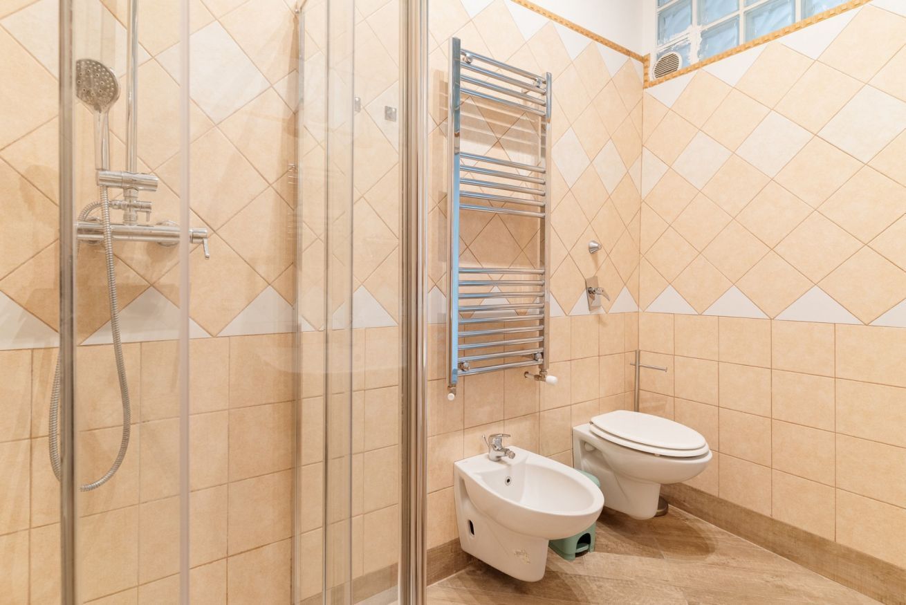 A bathroom with a glass-enclosed shower, a bidet, and a toilet.