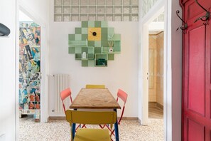 A dining area with a wooden table, chairs, and a green wall decoration.