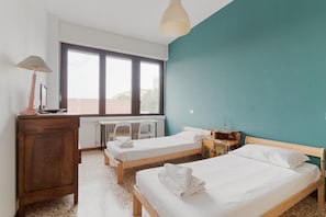 Un dormitorio con dos camas, un escritorio, una lámpara y un radiador.