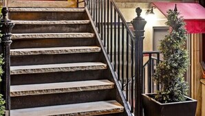 A staircase with a black railing leading to a door with a red awning. - Kasa the Duffy Times Square (New York)