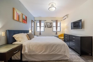 A bedroom with a bed, bedside table, dresser, TV, and artwork on the wall. - Kasa the Duffy Times Square (New York)