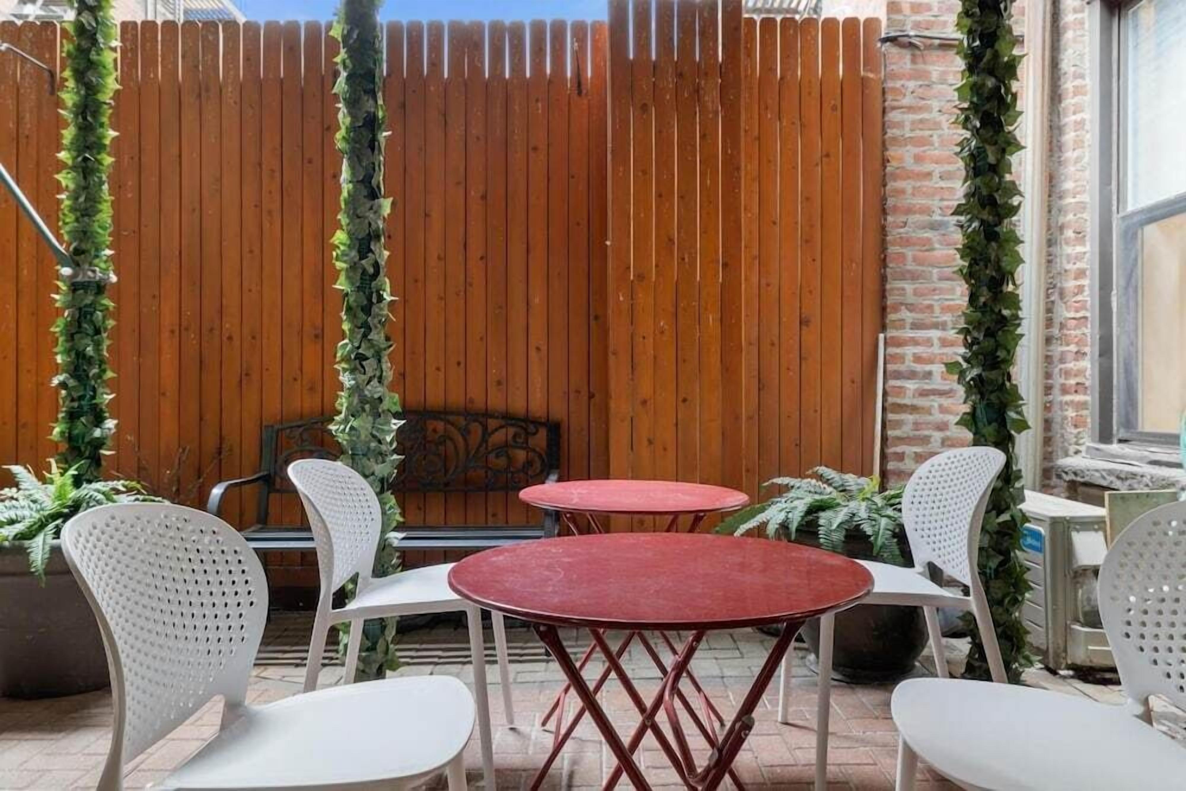 A patio area with two round tables and four white chairs.