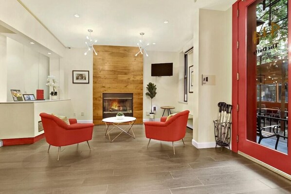 A modern lobby with a fireplace, red chairs, and a wooden accent wall. - Kasa the Duffy Times Square (New York)