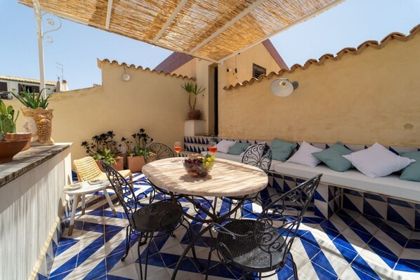 Une terrasse avec une table ronde, des chaises et un canapé avec des coussins.