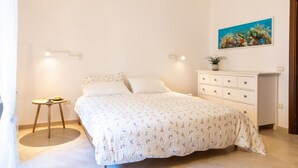 Ein Schlafzimmer mit Bett, Nachttisch, Schminktisch und einem Bild an der Wand.