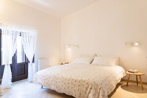 Une chambre à coucher avec un lit, des tables de chevet, une fenêtre avec des rideaux et un radiateur.