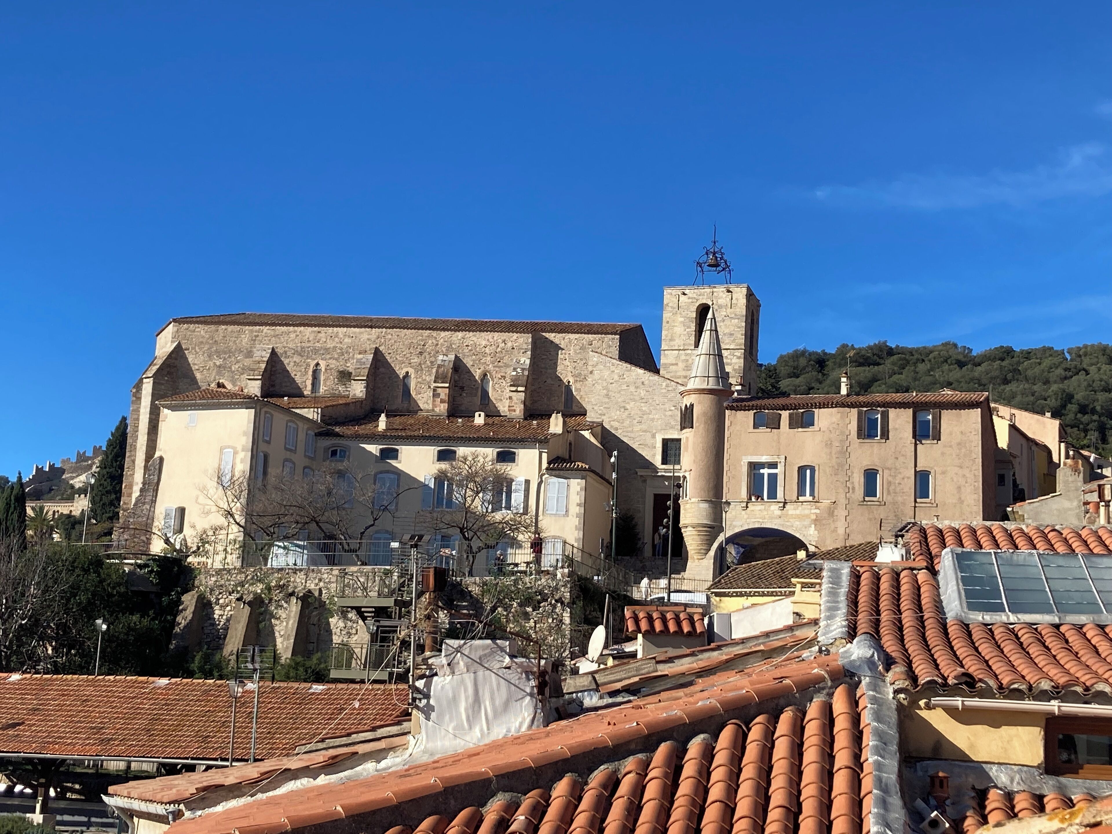A historic building with a bell tower, stone walls, and terracotta roofs.