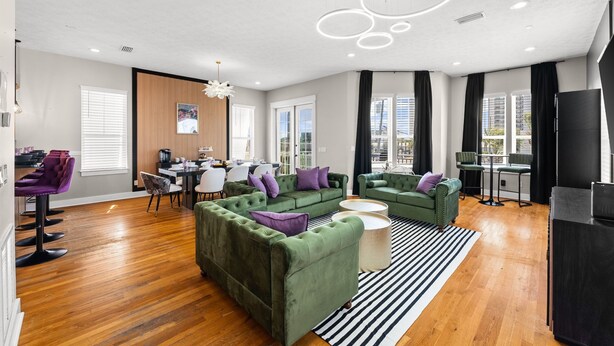 A modern living room with green sofas, a dining area, and a kitchen.