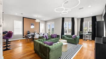 A modern living room with green sofas, a dining area, and a kitchen.