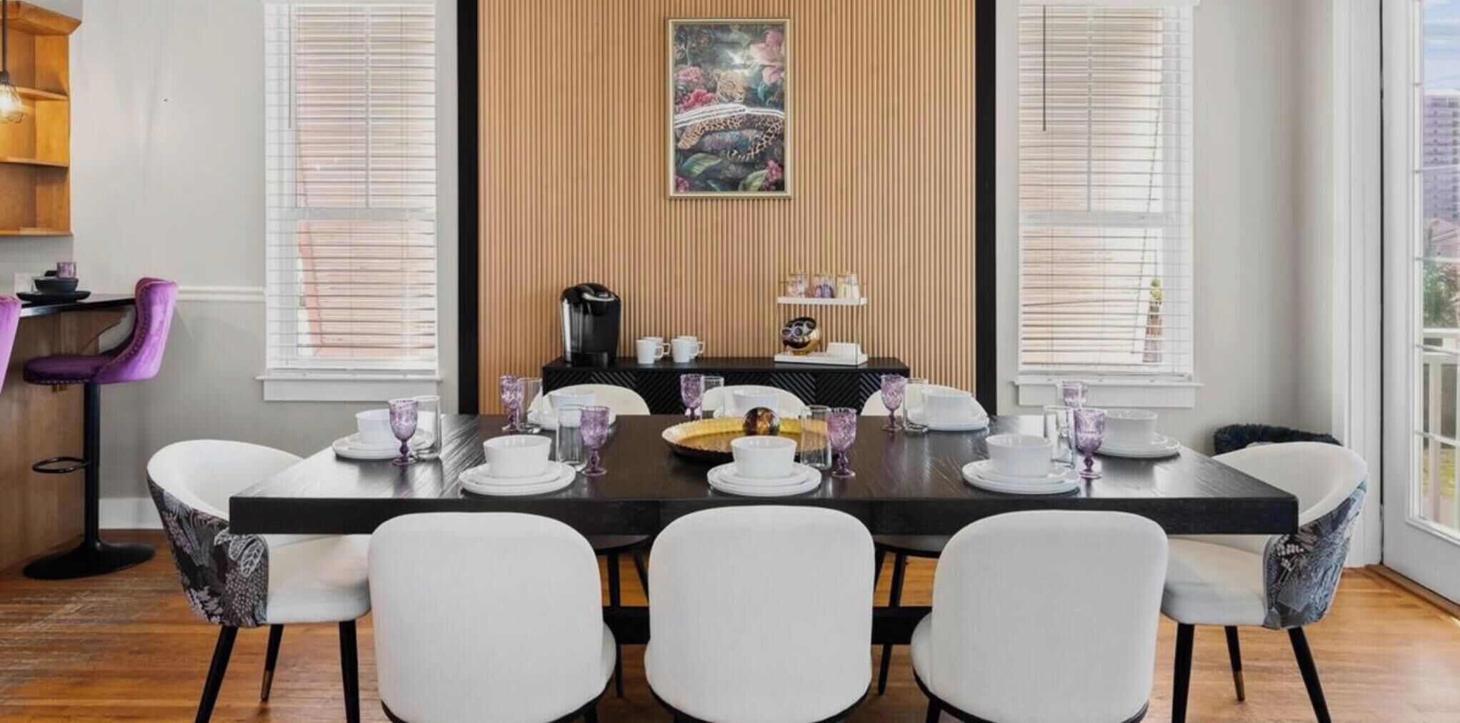 A dining area with a long table set for six, white chairs, and a central decorative piece.