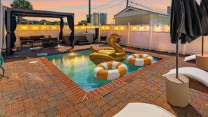 A rooftop pool area with a swan-shaped float, lounge chairs, and a covered seating area.