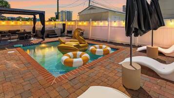 A rooftop pool area with a swan-shaped float, lounge chairs, and a covered seating area.