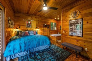 Une pièce de style cabane en bois, avec un lit, un banc, une baignoire et une affiche accrochée au mur.
