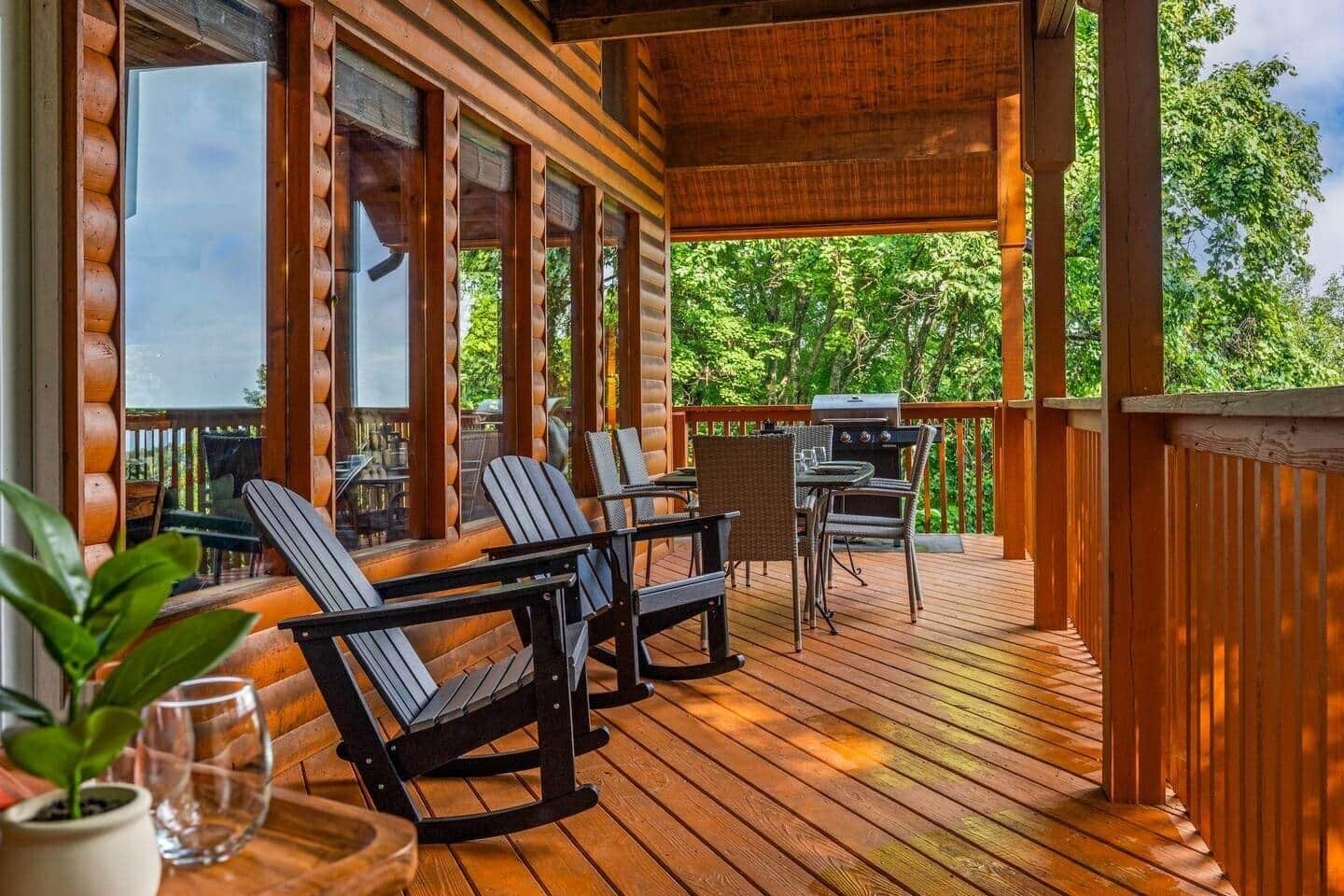 A wooden deck with outdoor seating, a grill, and a view of trees.