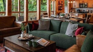 A cozy cabin interior with a wooden ceiling, a dining area, and a living room furnished with a sofa and a coffee table. - Legends Lookout! Mtn Views, Bear sightings & More (Gatlinburg)