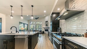 Cozinha moderna com ilha central, eletrodomésticos de aço inoxidável e painel de backsplash de tijolos.