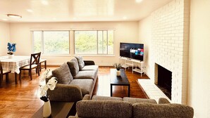 Una sala de estar con sofá, televisión, chimenea y comedor con mesa y sillas.