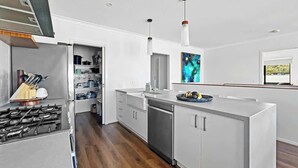 Una cocina moderna con una isla central, electrodomésticos de acero inoxidable y vistas al exterior.