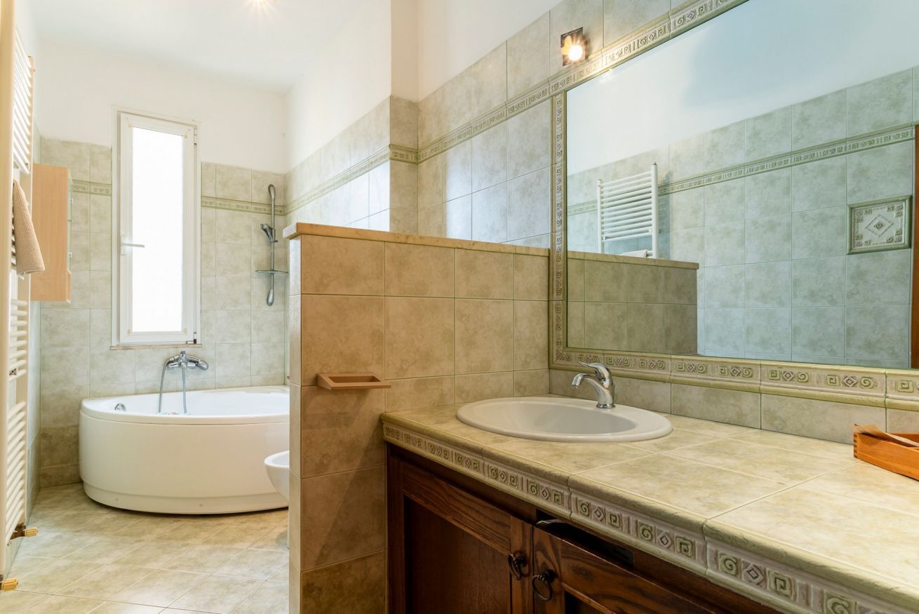 A bathroom with a bathtub, a sink, and a large mirror.