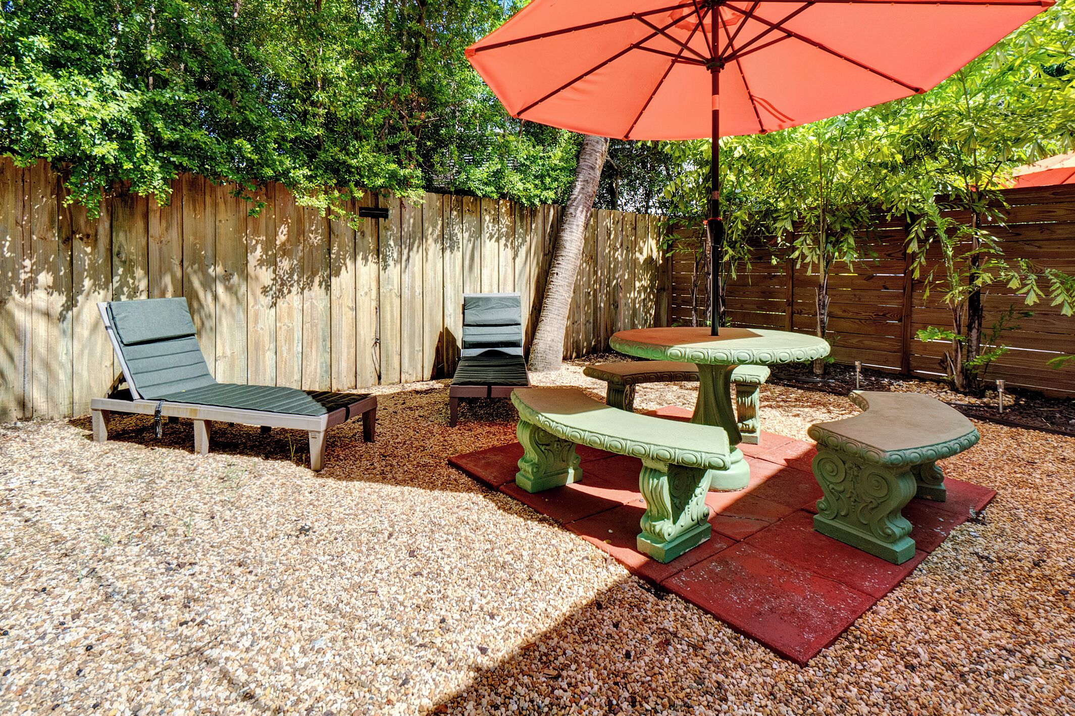 Un espace extérieur aménagé avec un fauteuil de relaxation, une table et un parasol.