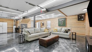 A modern living room with a sectional sofa, a coffee table, and a wooden accent wall. - Secluded 10-acre villa, sleeps 18, hot tub! (Trenton)