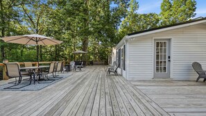 Eine Holzterrasse mit Gartenmöbeln, einem Grill und einem überdachten Sitzbereich.