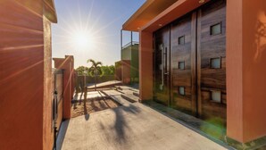 A modern building with a concrete pathway leading to a wooden door with glass panels. - 5BR/5B bath Los Barriles Retreat w/ Pool, Hot Tub & Sea of Cortez Views (Buenos Aires)
