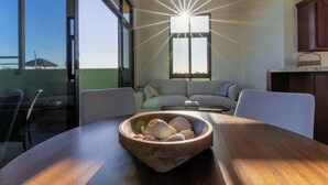 A modern living room with a wooden table, a bowl of seashells, a sofa, and a large window with natural light. - 5BR/5B bath Los Barriles Retreat w/ Pool, Hot Tub & Sea of Cortez Views (Buenos Aires)
