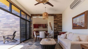 A modern living room with a sofa, a wicker coffee table, and a dining area with chairs and a table. - 5BR/5B bath Los Barriles Retreat w/ Pool, Hot Tub & Sea of Cortez Views (Buenos Aires)