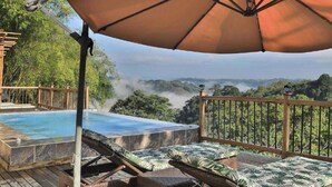 A pool area with a wooden deck, lounge chairs, and a large umbrella. - Anahari Centro Wellness (Quimbaya)