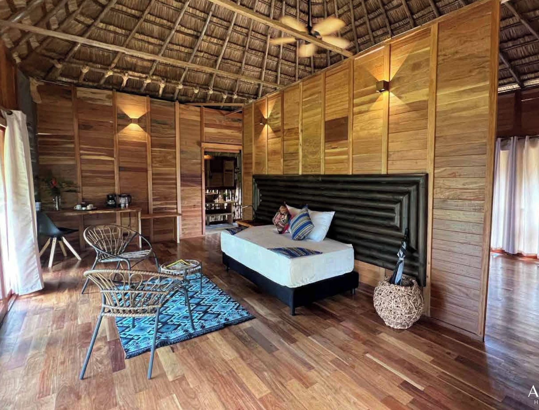 Une chambre spacieuse avec un grand lit, des murs en bois et un ventilateur de plafond.