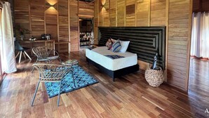 A spacious bedroom with a large bed, wooden walls, and a ceiling fan. - Anahari Centro Wellness (Quimbaya)