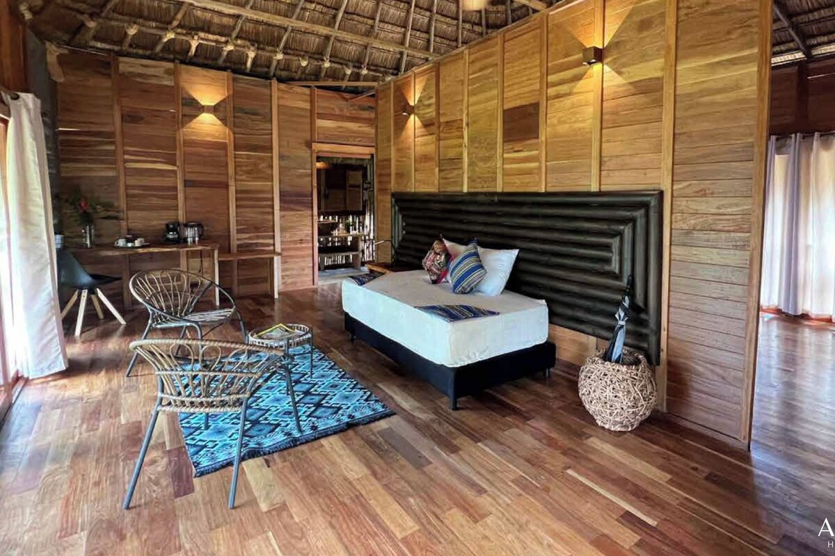 A spacious bedroom with a large bed, wooden walls, and a ceiling fan.