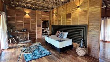 Quarto espaçoso com cama grande, paredes de madeira e ventilador de teto.
