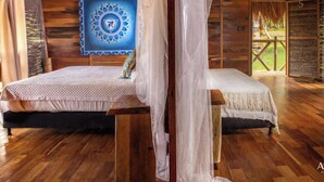 A wooden room with a bed, a small table, and a wall with a blue and white design. - Anahari Centro Wellness (Quimbaya)