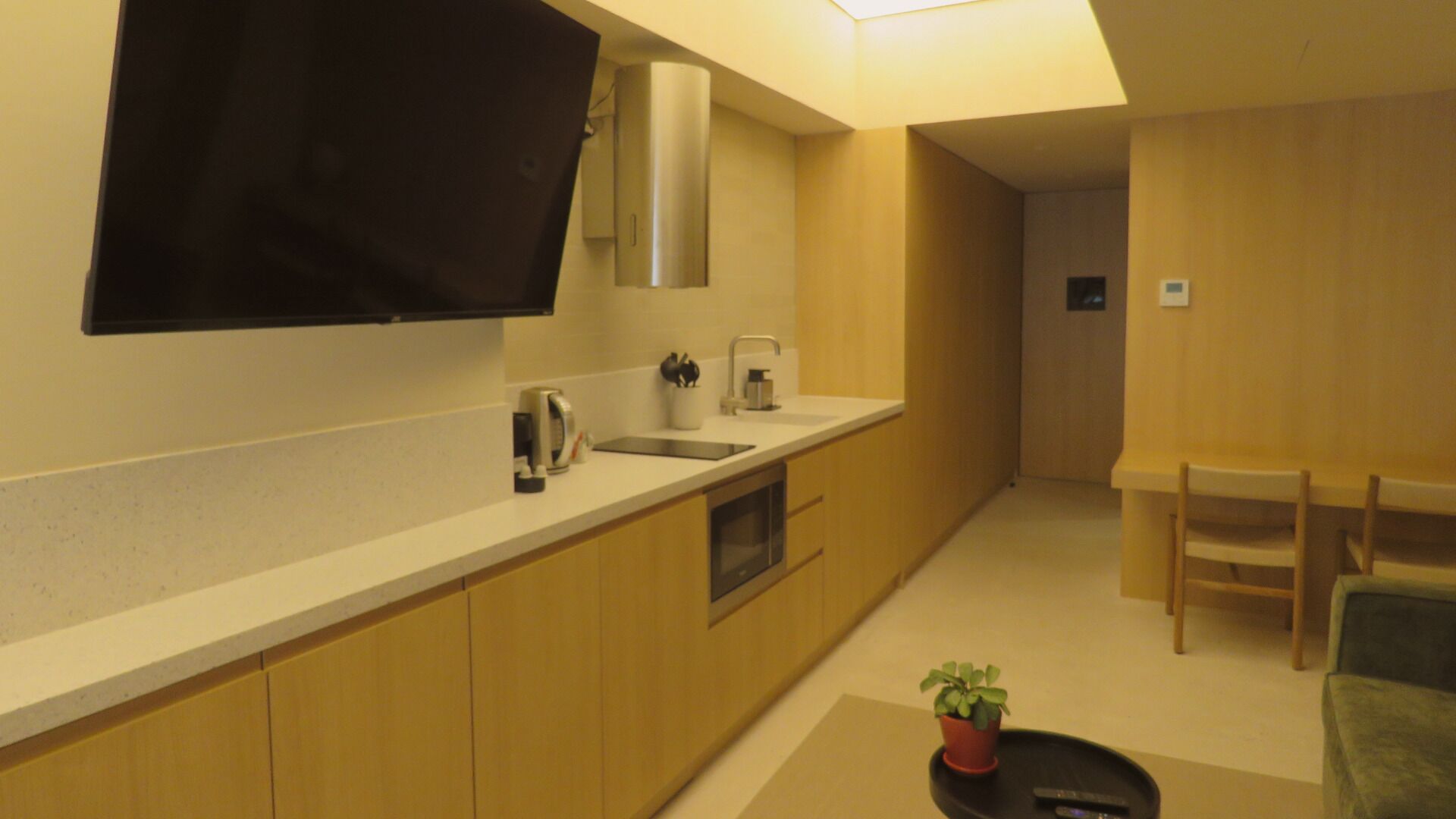 A modern kitchen with a flat-screen TV, a microwave, and a sink.
